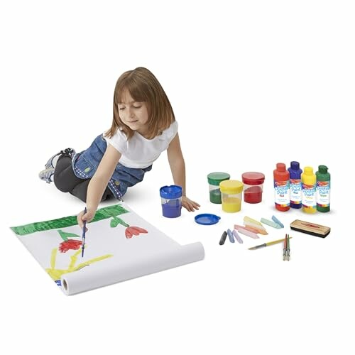 Child painting on paper with art supplies.