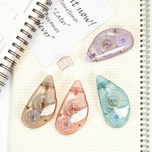 Colorful correction tape dispensers on open notebooks with handwritten notes.