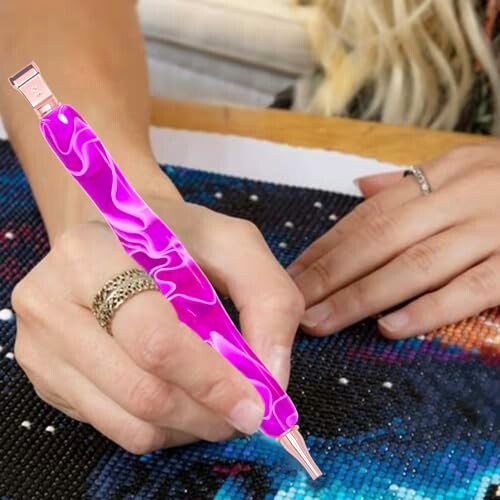 Person using a diamond painting tool on a canvas.