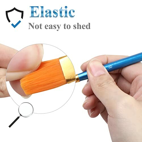 Close-up of a person holding an elastic paintbrush with orange bristles.