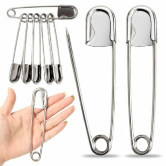 Large metal safety pins with a hand showing size comparison.