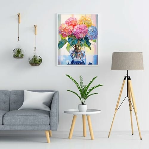Modern living room with gray sofa, indoor plants, and colorful floral painting.