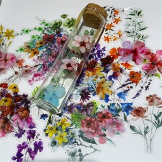 A glass tube containing pressed flowers on a background of colorful floral designs.