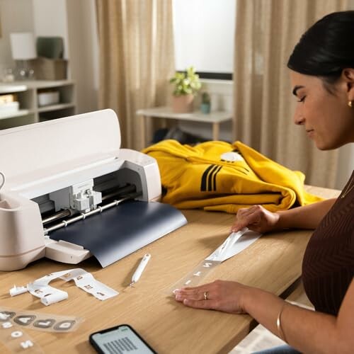 Woman using a cutting machine to create vinyl letters at home.