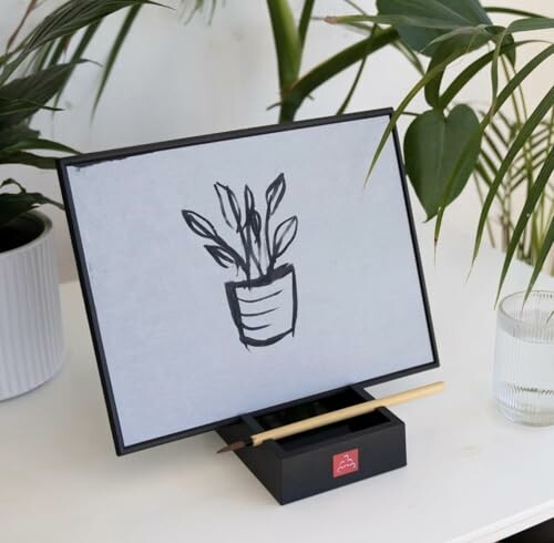Zen board with plant drawing beside potted plants and a pencil.